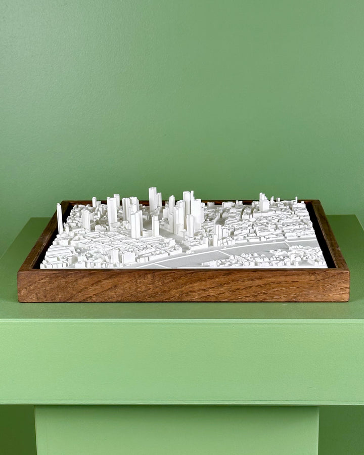 3D cityscape model of Frankfurt in a wooden frame on a green surface with a green background