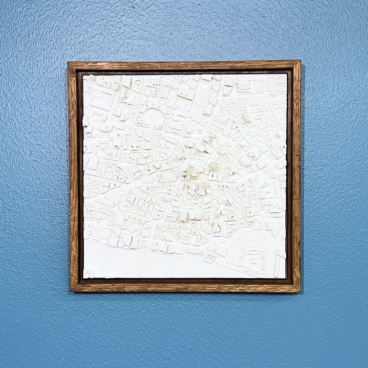 3D model of London in a dark colour oak frame. London cityscape model hanging on a blue wall.