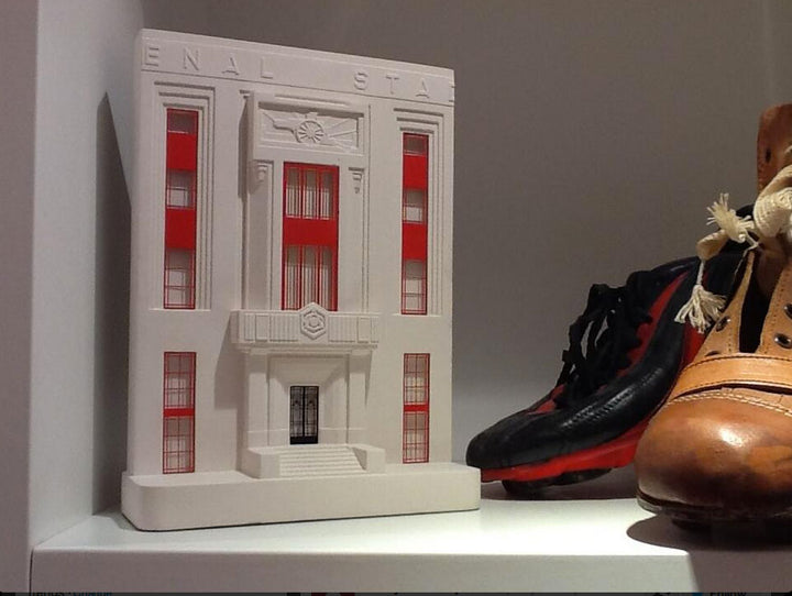 Arsenal's Highbury Stadium architectural scale facade model on a shelf with football boots